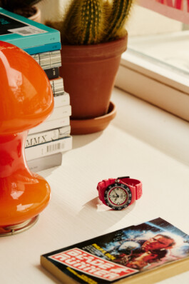 Photograph by Roderick Aichinger for Esquire Germany magazine. The image features a striking red Tag Heuer watch placed on a light-colored table, surrounded by an orange lamp, a potted cactus, a stack of modern books, and a Blade Runner book. The composition highlights contemporary style and watch design in a curated lifestyle setting.