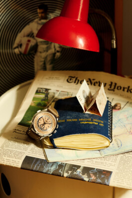 Photograph by Roderick Aichinger for Esquire Germany, fall 2025 issue. The image showcases a Patek Philippe World Time Chronograph Flyback (ref. 5935A-001) with a salmon-colored dial and brown calfskin strap, elegantly placed on a travel diary and The New York Times, with travel-themed elements in the background. The composition evokes vintage adventure and refined globetrotting, highlighting the technical and visual sophistication of the Patek Philippe World Time Chronograph.