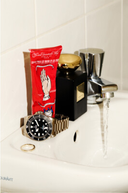 Photograph by Roderick Aichinger for Esquire Germany, fall 2025 issue. The image features the Tudor Black Bay 68, a professional dive watch with black dial, Snowflake hands, and stainless steel bracelet, positioned beside hand cream and a perfume bottle at a running sink. The composition highlights the robust and contemporary design of Tudor’s latest diver, emphasizing versatility and luxury.