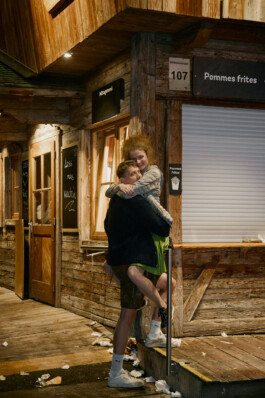 A couple is embracing outside a rustic wooden food stand labeled