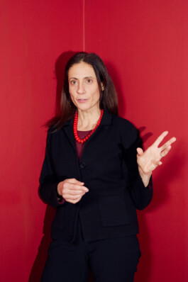 Nathalie Tocci stands in front of a red wall, gesturing while speaking during the “World in Pieces” symposium at Schloss Elmau.