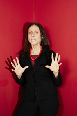Nathalie Tocci stands in front of a red wall, gesturing while speaking during the “World in Pieces” symposium at Schloss Elmau.