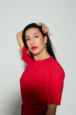 Tijen Onaran poses in a red outfit against a white background
